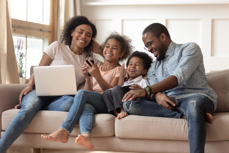 Cheerful,African,Parents,And,Kids,Laugh,Use,Devices,Together,Sit